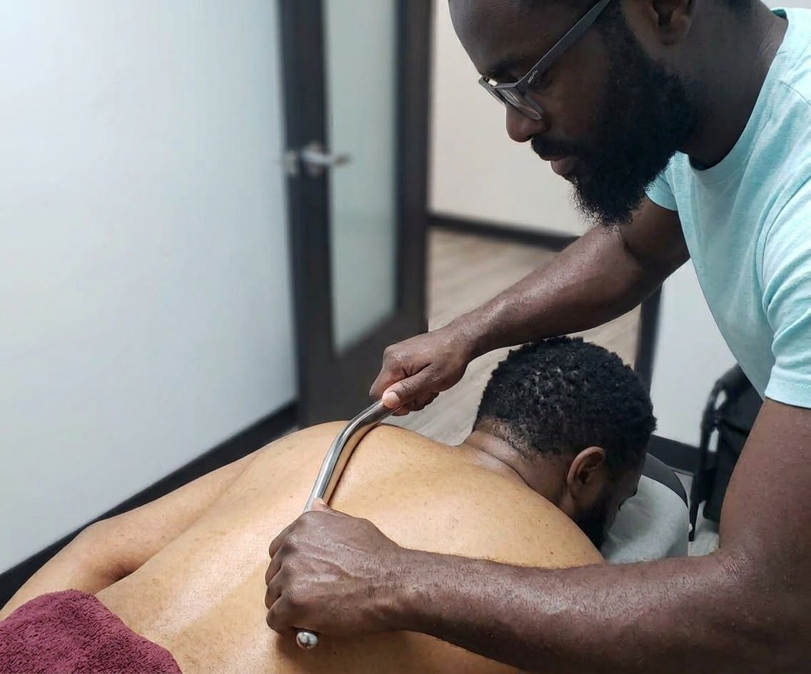 Tunde using a Graston instrument on a client's upper back