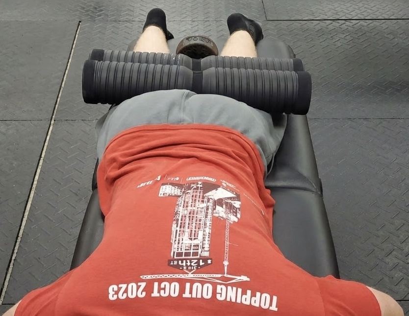 Weighted rollers resting across a client's hamstrings during body tempering